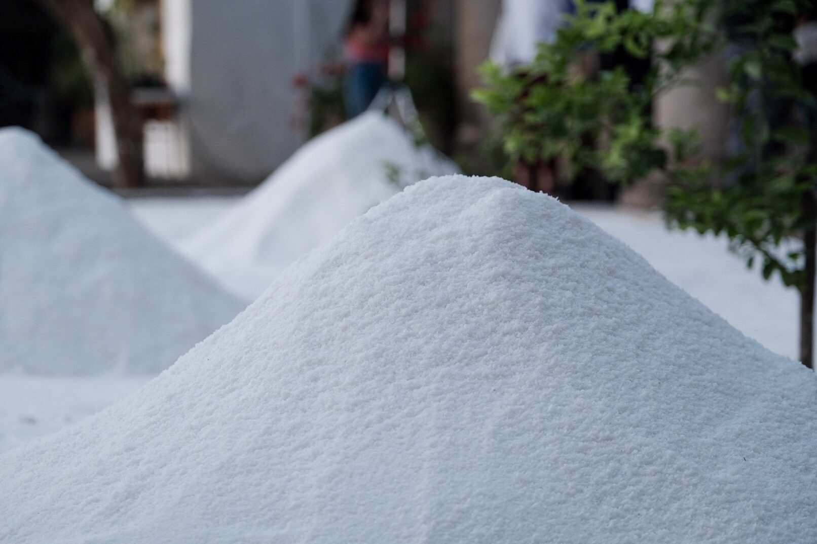 An image of 3 large piles of salt in a field of salt